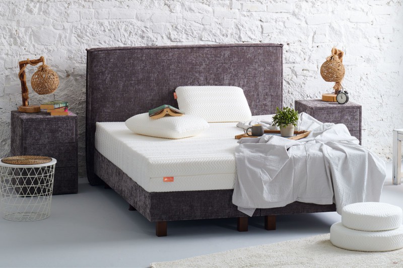 witte matras op grijs bed met witte kussens in een slaapkamer