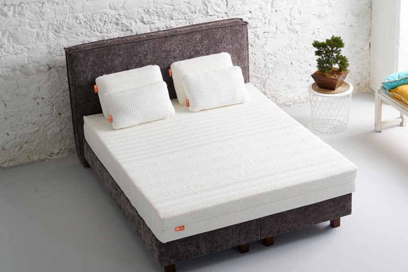 witte matras op grijs bed met 4 witte kussens in een slaapkamer