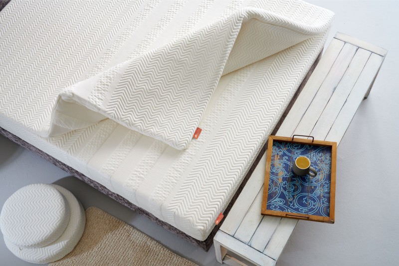 witte topmatras op witte matras met bijzettafel met dienblad en koffie