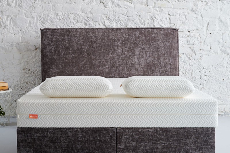 witte latex hoofdkussens op een bed met grijs hoofdbord