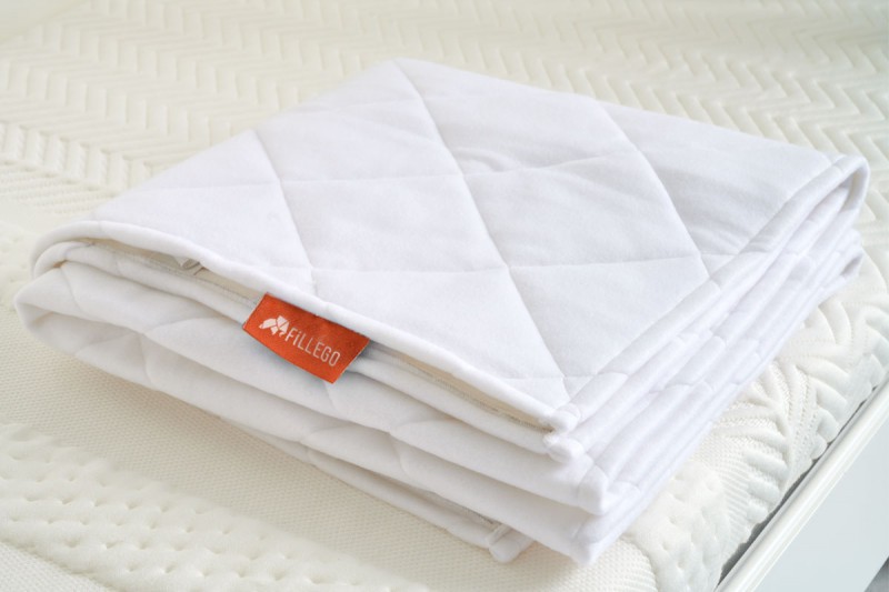witte matras beschermer opgevouwen op een wit bed